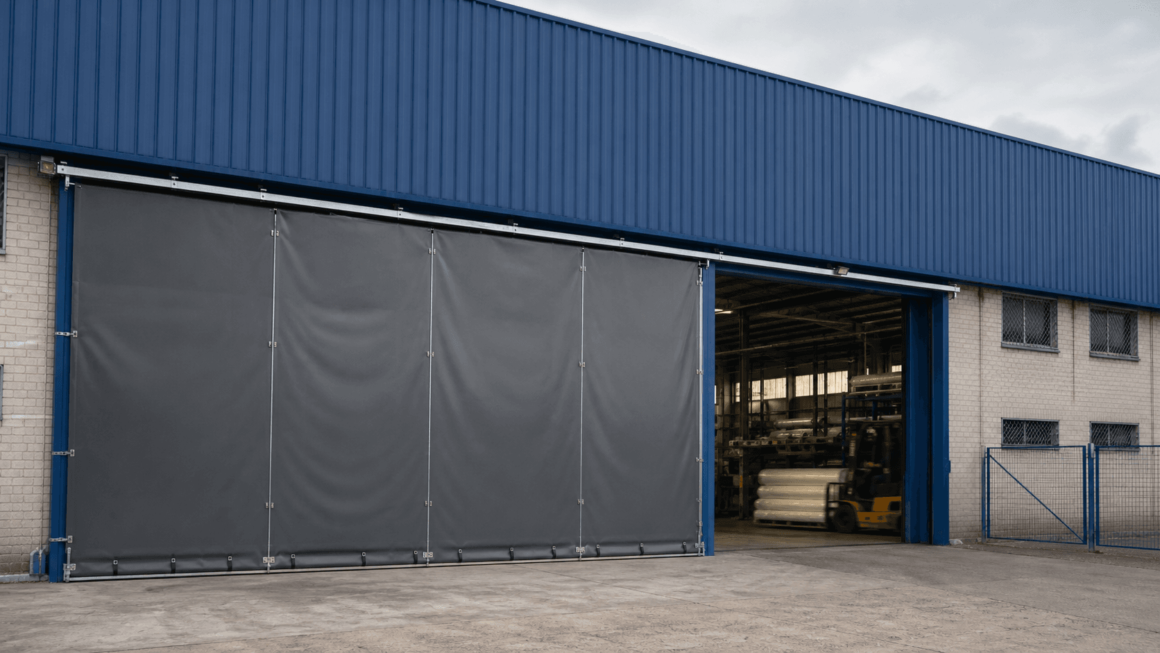 Cerramiento textil gris instalado en el acceso de una nave industrial